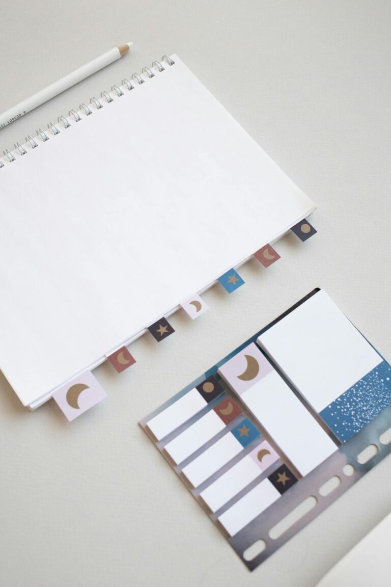 Top view of a blank spiral notebook with pastel sticky notes on a white surface, ideal for mockups.